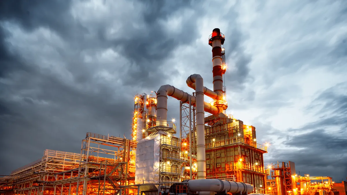 Planta petroquímica iluminada sob céu nublado