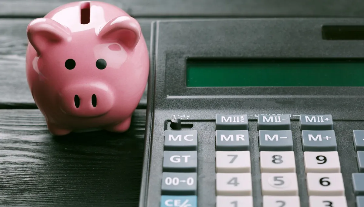 Cofre em formato de porquinho ao lado de calculadora